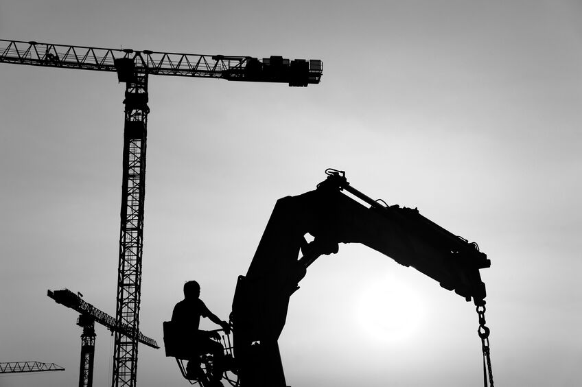 silhouette of crane and worker in construction site