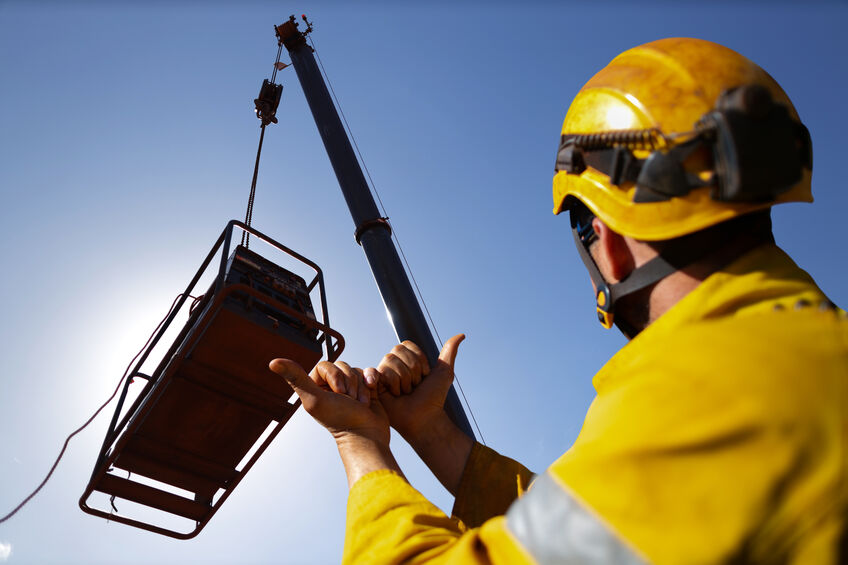 safe work practice crane rigger wearing protection helmets giving crane operator hand signal by holding up two hand against each other pointing both thumbs out meant crane boom is good to go 